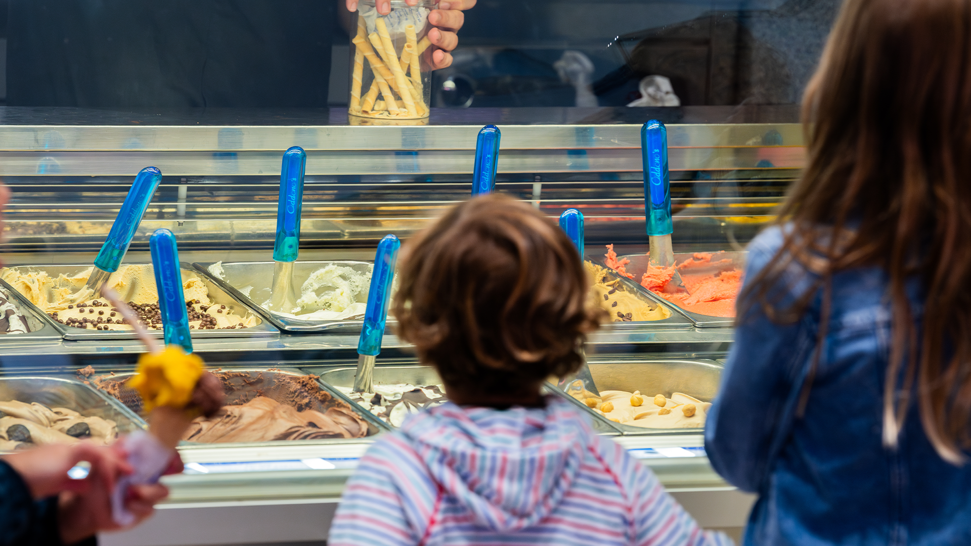 Two children look on at the trays of ice cream from behind the glass counter