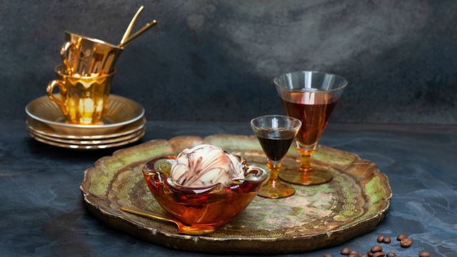 A  large golden tray with glass goblets of coffee and a large glass bowl filled with mocha ice cream.