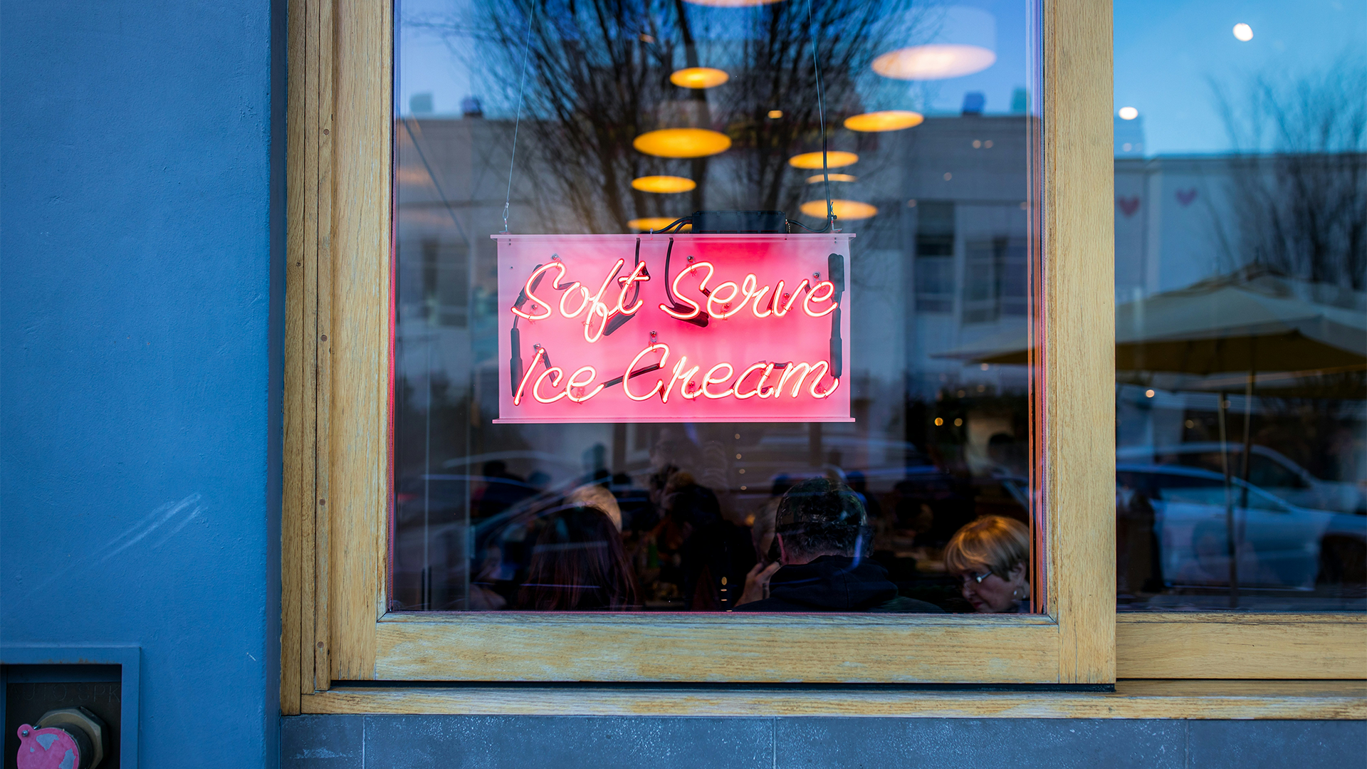 A pink neon sign outside an ice cream shop with the words "soft serve ice cream"