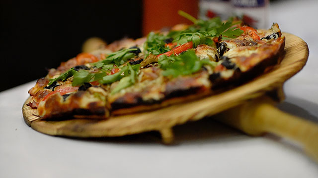 Eine Pizza euf einem hölzernen Servierbrett