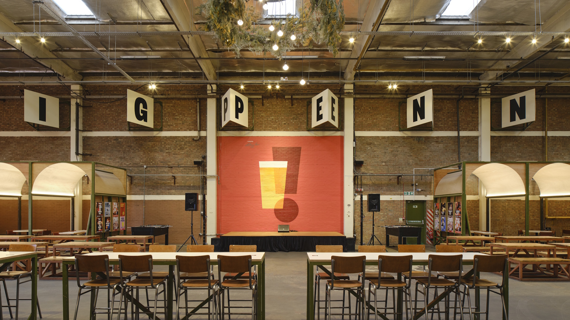 Inside the beer hall at Big Penny Social, with high tables, stools and brick walls.