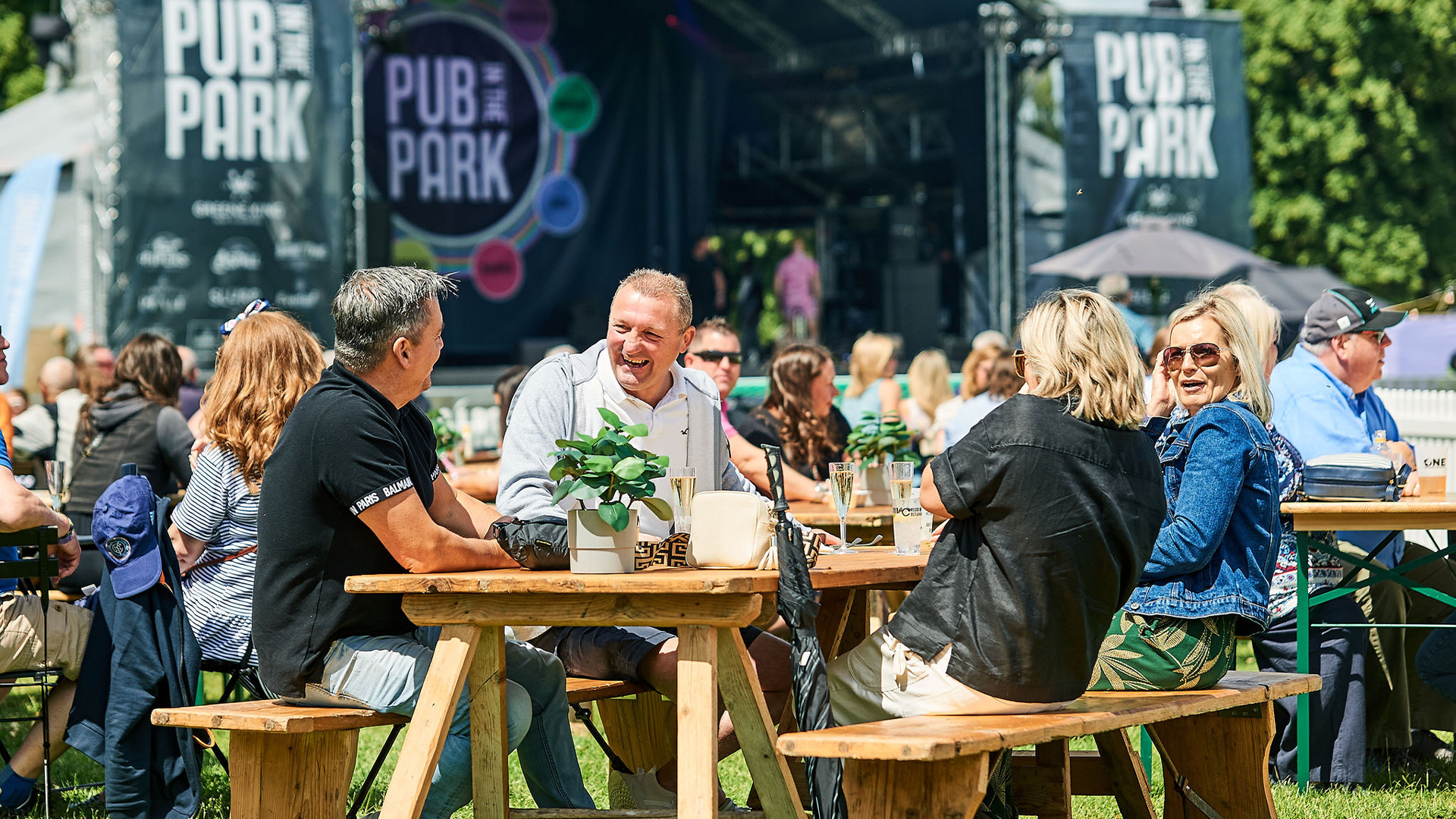A group of people sat on a bench outside at Pub in the Park
