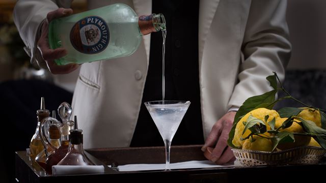 A waiter in a white jacket pours gin into a chilled martini glass on a trolley at Duke's Bar.