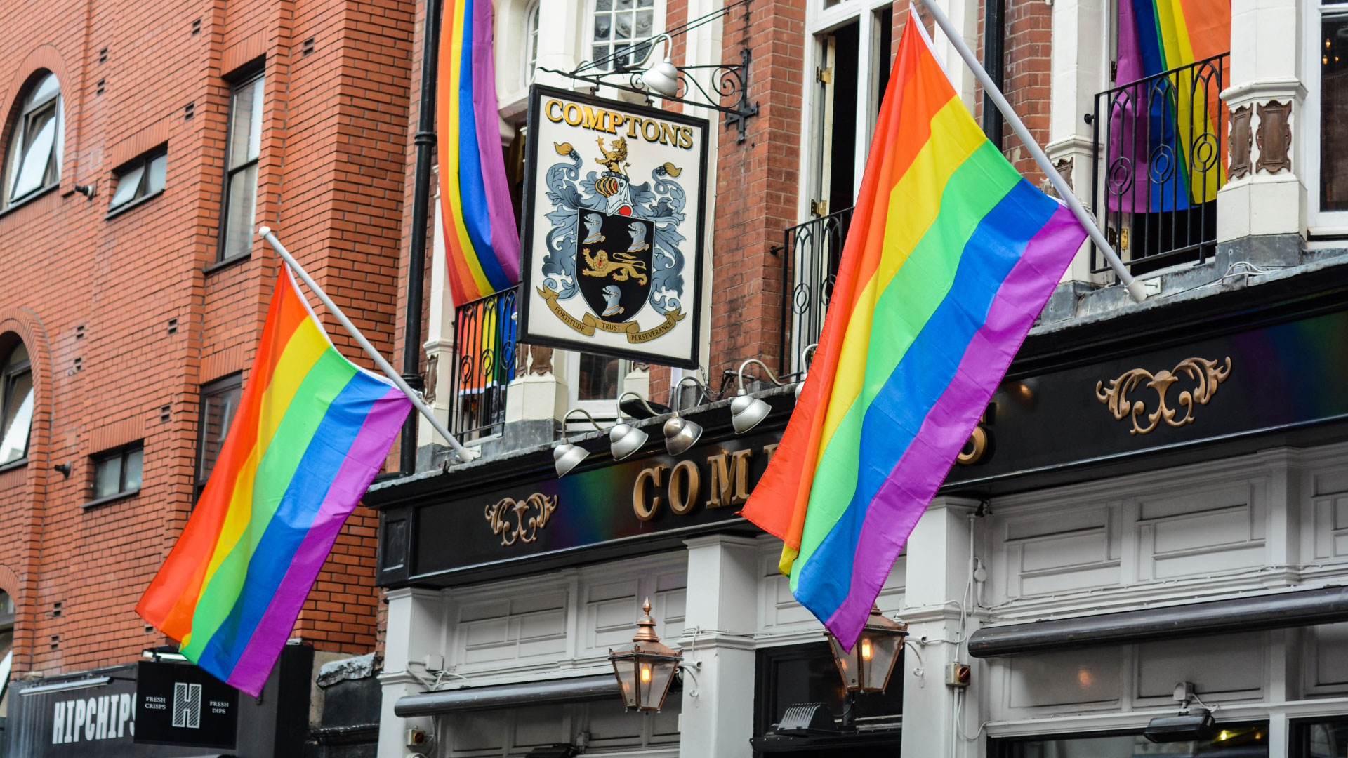 A photo of the exterior of Comptons pub in Soho with LGBTQ+ flags hanging from the outside