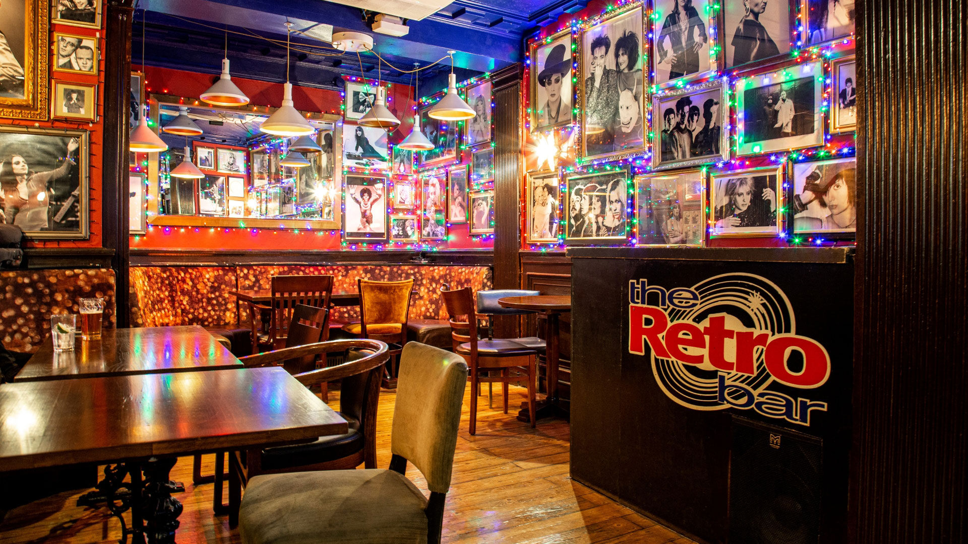 A photo of the interior of Retro Bar with photos of rock and pop musicians covering the walls, colourful lights and comfy chairs and tables