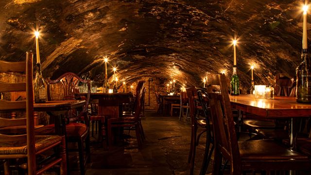 Tables with candles in the centre in the cellar of Gordon's Wine Bar.