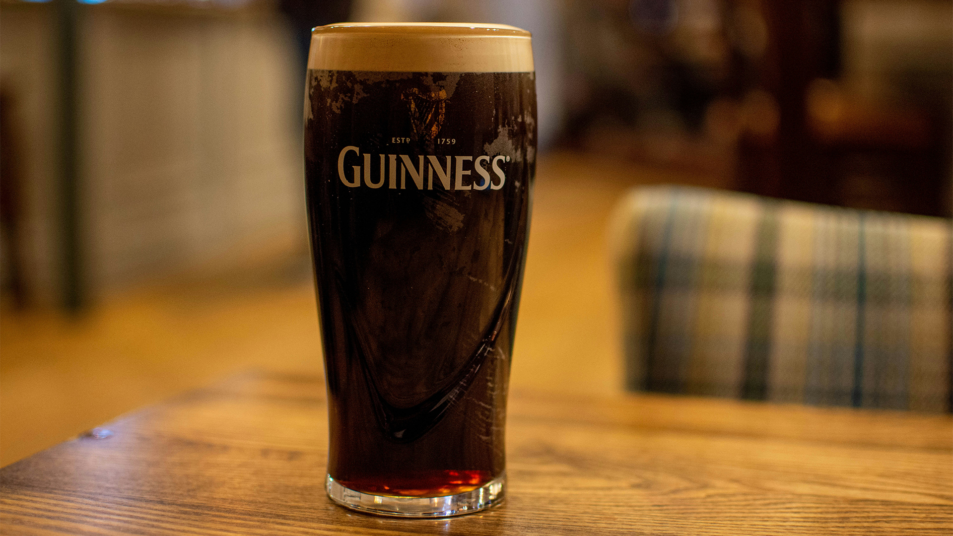 A glass of Guinness sitting on a wooden table