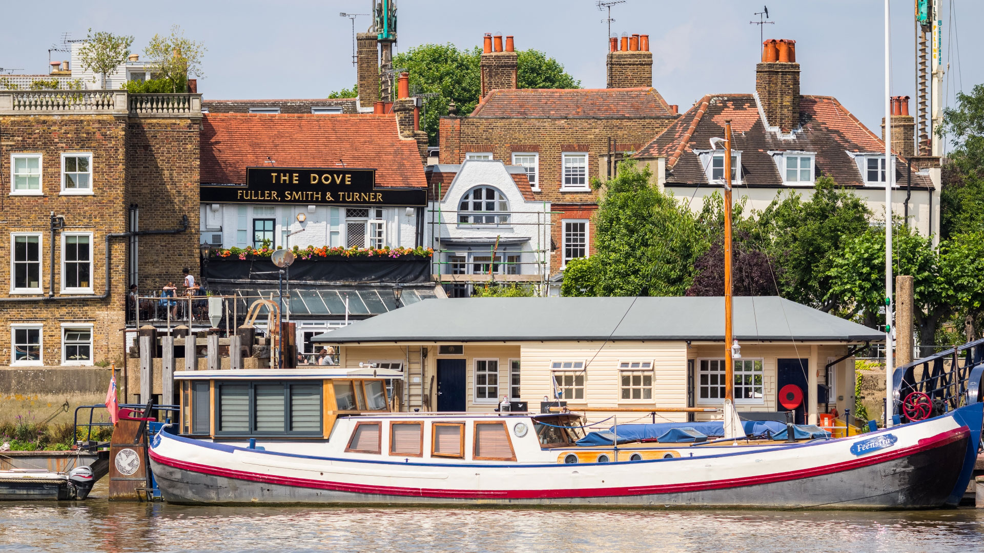 A photo of the exterior of The Dove in Hammersmith with a boat on the Thames in the foreground