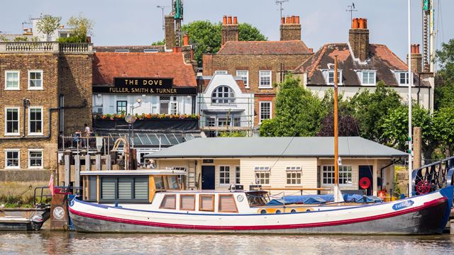A photo of the exterior of The Dove in Hammersmith with a boat on the Thames in the foreground