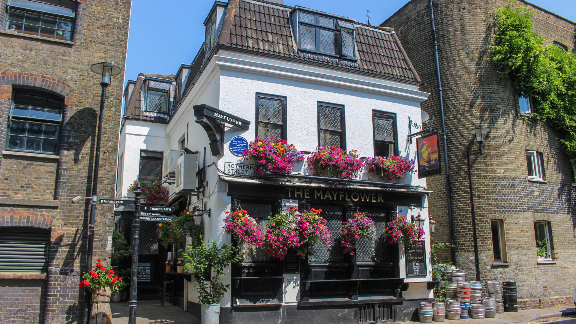 A photo of the exterior of the Mayflower pub, an old white building with elaborate pink flowers falling from its windows