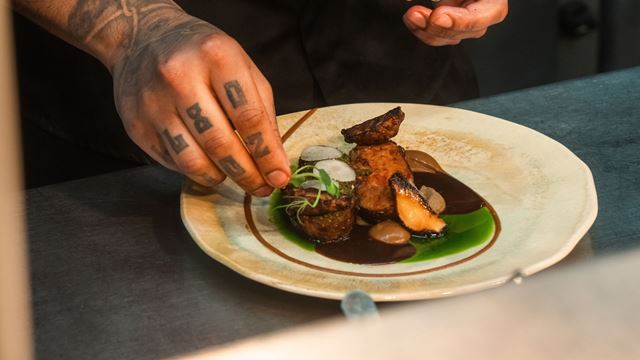 Chef putting garnish onto a plate of food at 2210 by NattyCanCook restaurant.
