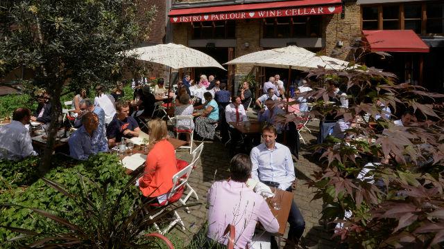 People sit outside on a restaurant terrace under umbrellas at the bleeding heart bistro.