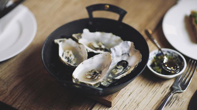 A skillet holding four large oysters.