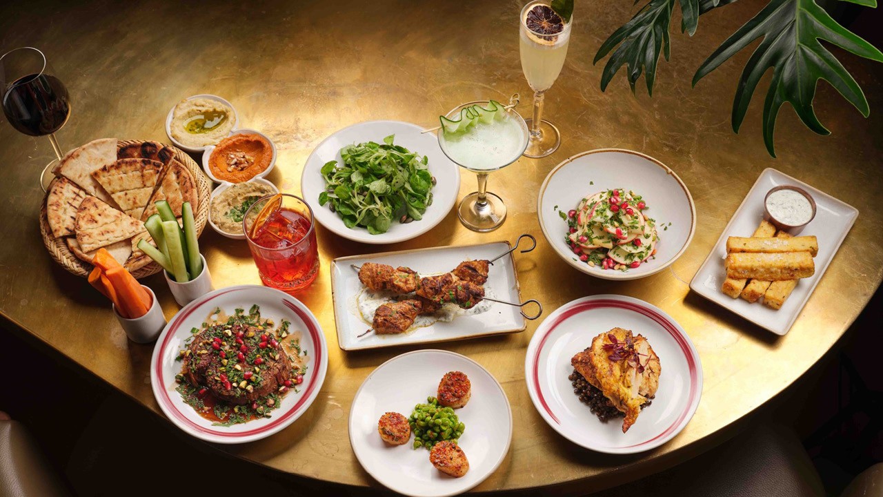A birds eye shot of different Middle Eastern dishes from CERU on a table with a glass of bubbles