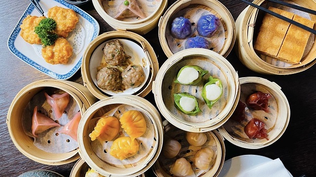 An assortment of colourful dim sum in small wicker baskets