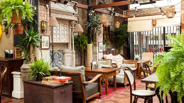 Dishoom Shoreditch. Image courtesy of Dishoom. The dining area at Dishoom Shoreditch with hanging plants, cosy sofas and a tiled floor.