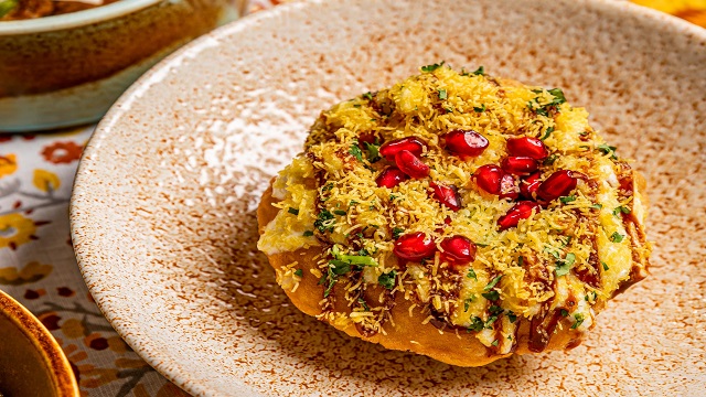 a cream bowl speckled with an orange pattern, with an Indian dish presented in the middle