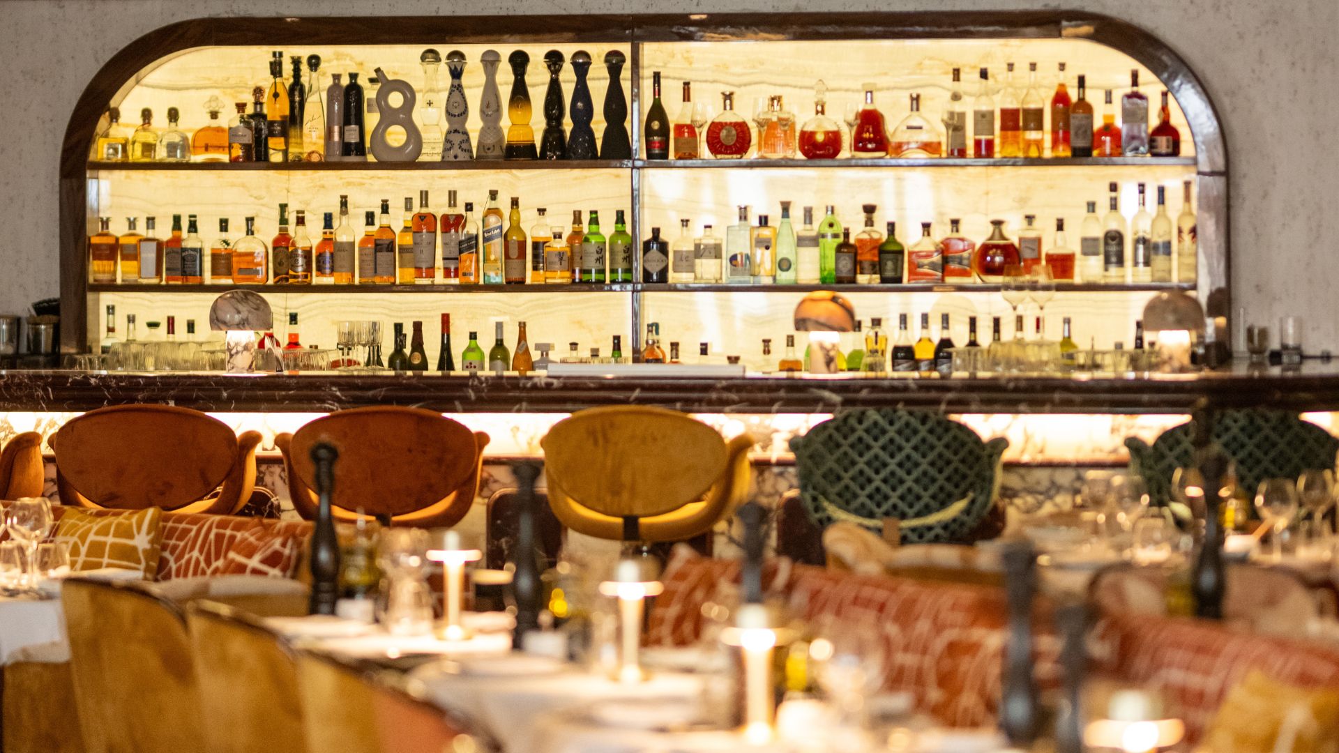 A warmly lit bar in la mome restaurant with plush furniture.