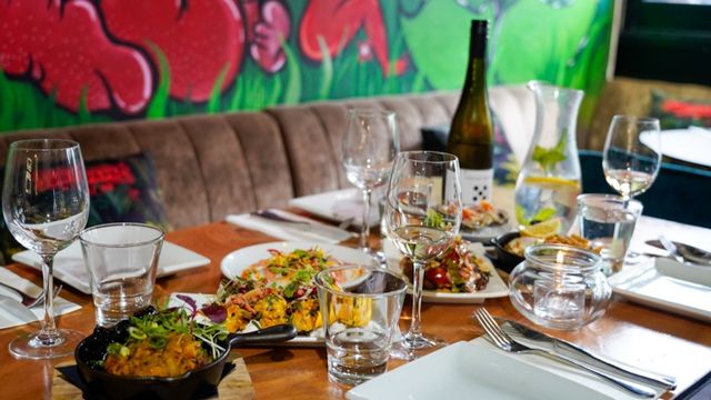 A table with glasses, cutlery a bottle of wine and a selection of Filipino fusion dishes.