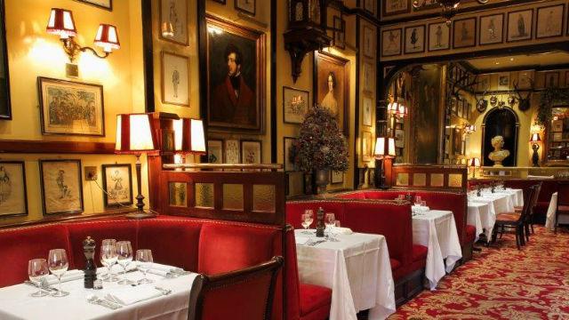 The interior of Rules restaurant with banquettes, white tablecloths and paintings on the walls.