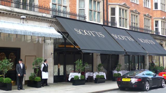 Two doorman stand outside seafood restaurant scotts in london mayfair. 