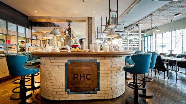 A beige restaurant with a round dining counter and large blue stools.