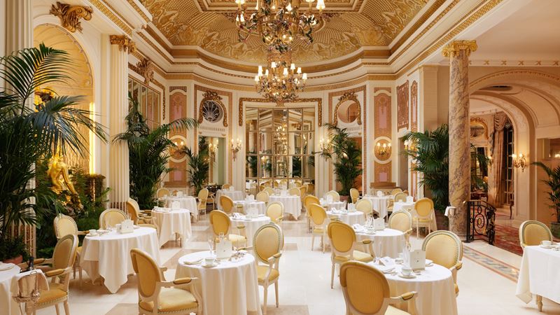 Experience a fabulous meal in romantic surroundings at The Ritz. Credit: The Ritz. Image courtesy of The Ritz. The Palm Court dining room at The Ritz London, complete with elegantly dressed tables, yellow chairs, chandeliers and plants.