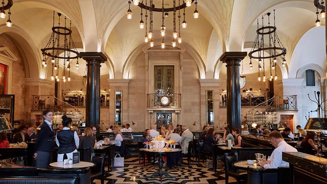 The interior of The Wolseley, with black-and-white tiled floors, chandeliers and vaulted ceilings.