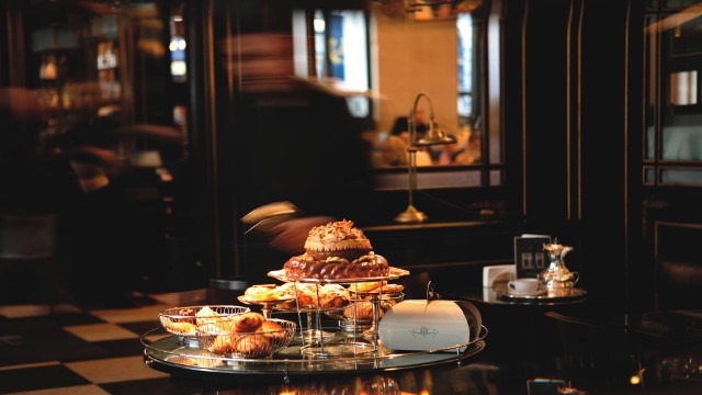 A darkened room in The Wolseley in Piccadilly with a table lined with pastries and cakes.