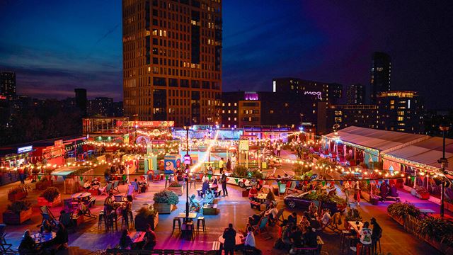 An evening aerial shot of Roof East's rooftop terrace and its neon lights