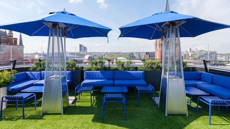 Discover panoramic views of the capital from The Standard, London hotel's rooftop terrace. Credit: The Standard, London. Image courtesy of The Standard. A photo of cobalt blue sofas and seats on the rooftop of The Standard with matching umbrellas and a view of the London skyline in the background