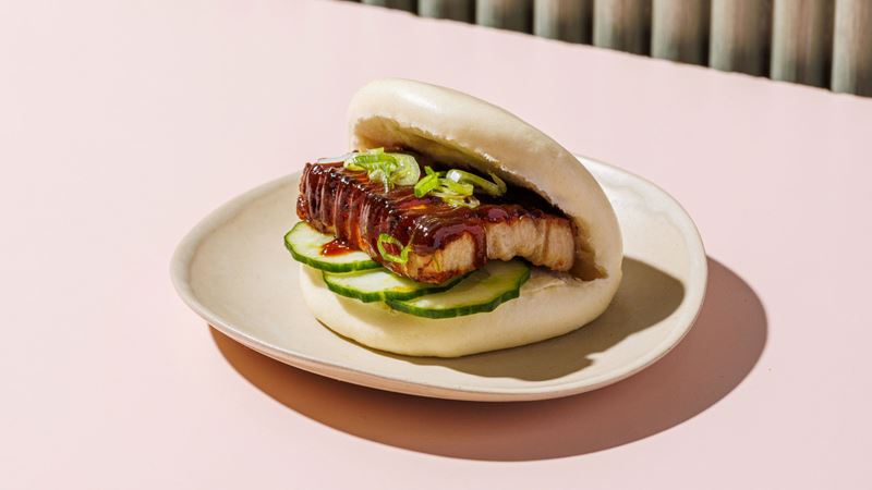 Take your pick from a selection of tasty filled bao buns at Yum Bun. Credit: Yum Bun. Image courtesy of Yum Bun. A photo of a bao bun on a plate filled with crispy tofu, cucumber, spring onions and a sticky brown sauce