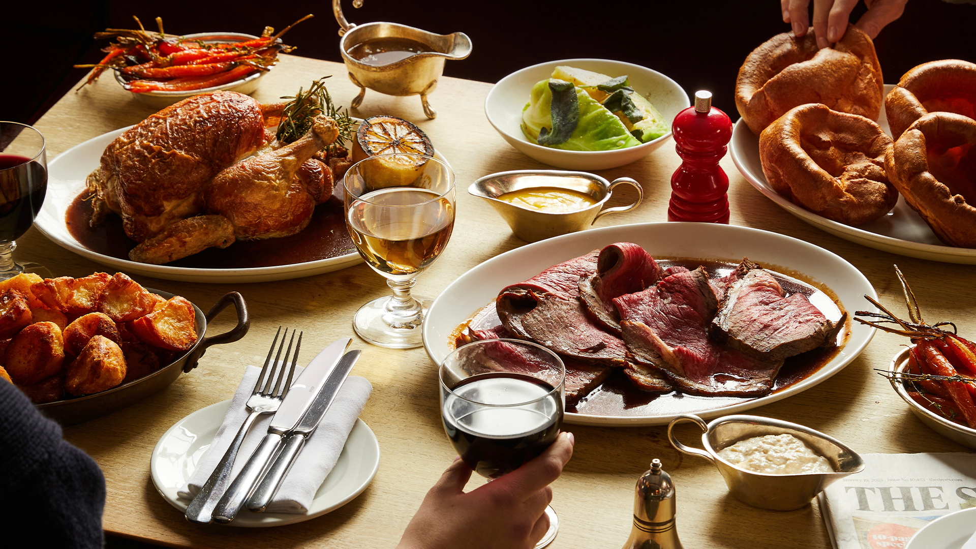 A spread of roast chicken, beef sirloin, roast potatoes, carrots, cabbage and gravy