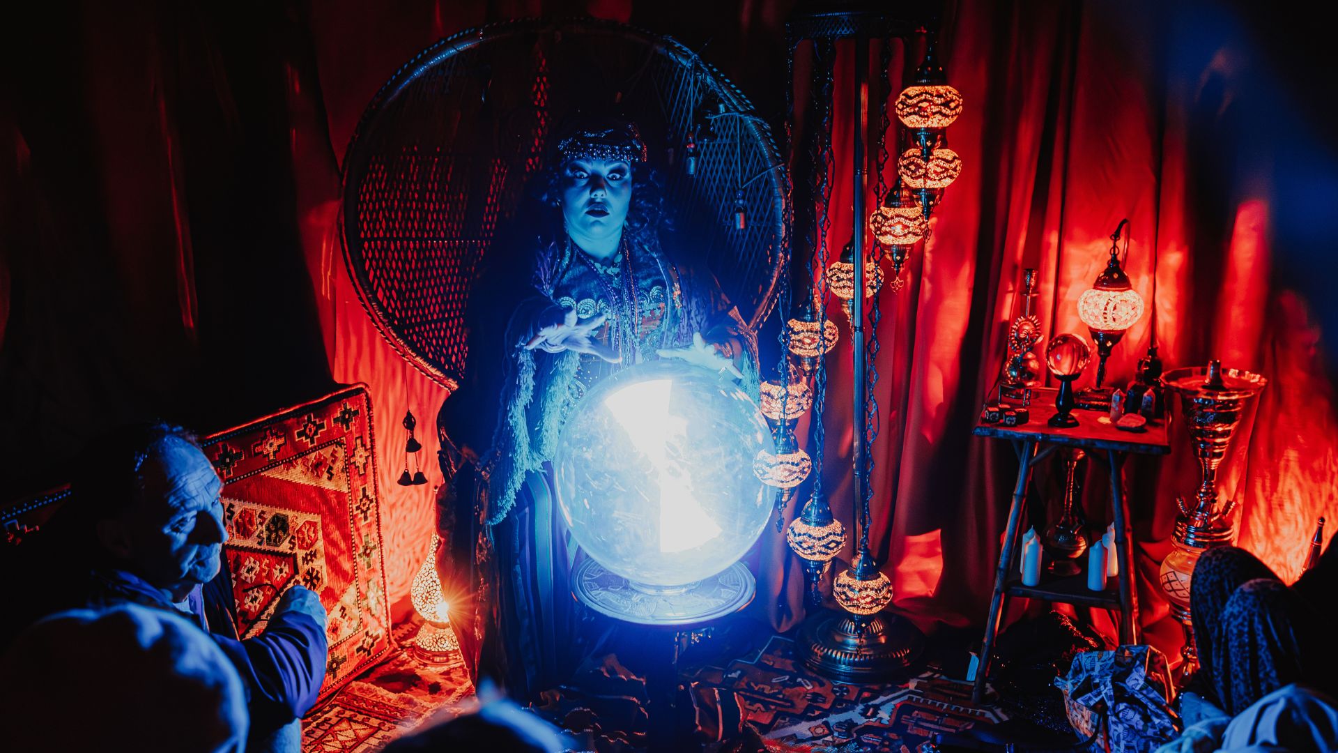 Enjoy a pre-show immersive adventure at COME ALIVE! London: The Greatest Showman Circus London Spectacular. © London Theatre Direct/Luke Dyson. fortune teller sat in a warm mood lit room, looking into a bright glass ball