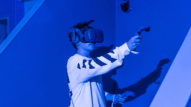 A boy in a blue VR pod wearing a VR headset playing a game