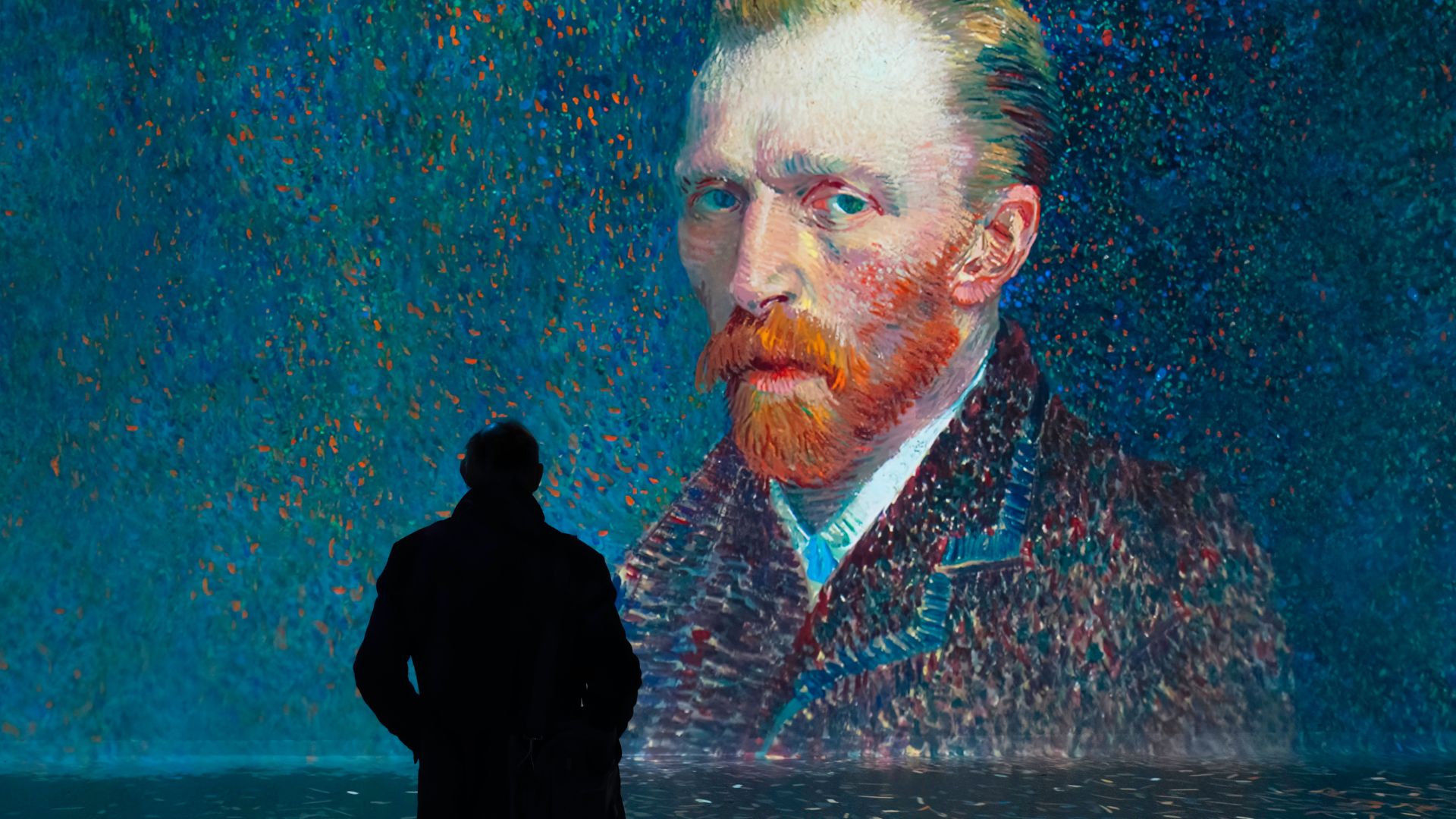 Treten Sie in der immersiven Ausstellung FRAMELESS mit den Künstlern in Kontakt. Bild mit Genehmigung von FRAMELESS. Ein Mann steht in einer Galerie vor Van Goghs Selbstporträt in der Ausstellung FRAMELESS in London.