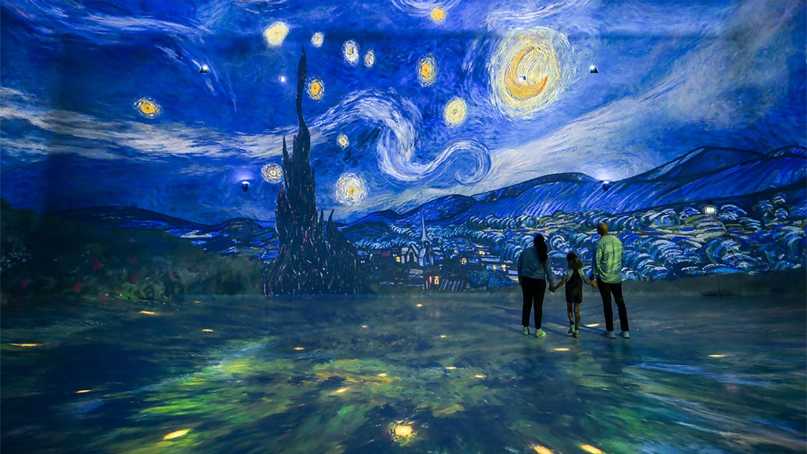 A family immersed in Van Gogh's Starry Night painting at FRAMELESS