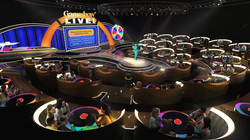 Step inside the spotlight at Gameshow LIVE! - London’s first live, interactive gameshow experience opening in 2026. Image courtesy of Mance Communications. Audience members seated in illuminated booths take part in a live gameshow experience with a host on a central stage and large screens.