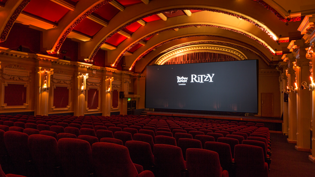 Arched ceiling above the film screen with warm lighting and red velvet cinema seats