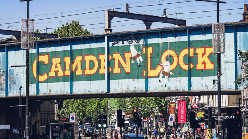 Visit famous Camden Lock for cool weekend vibes. Credit: London & Partners. Image courtesy of London & Partners. Bridge in Camden with iconic Camden Lock painted mural on the side in green and yellow