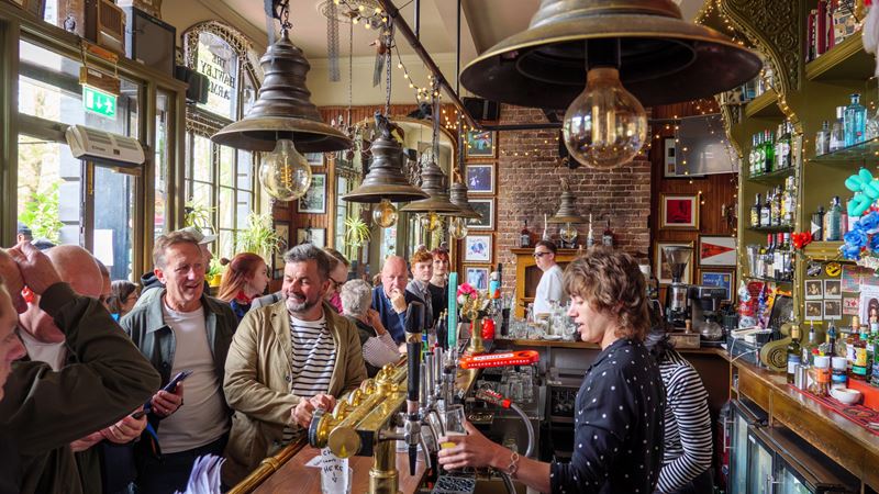 Sip on freshly poured pints in this popular local Camden pub. Credit: Shutterstock. Image courtesy of Shutterstock. A photo of the interior of The Hawley Arms pubs with crowds queuing for pints and two people taking orders behind the bar with retro and vintage decor lining the walls