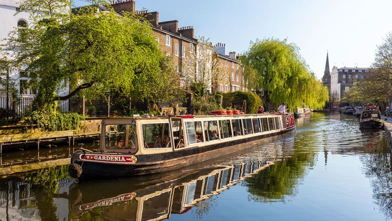 Visit Little Venice, the neighbourhood of Michael Bond, who wrote the Paddington Bear books. Credit: Jon Reid. Image courtesy of visitlondon.com. A boat travels along the water in Little Venice