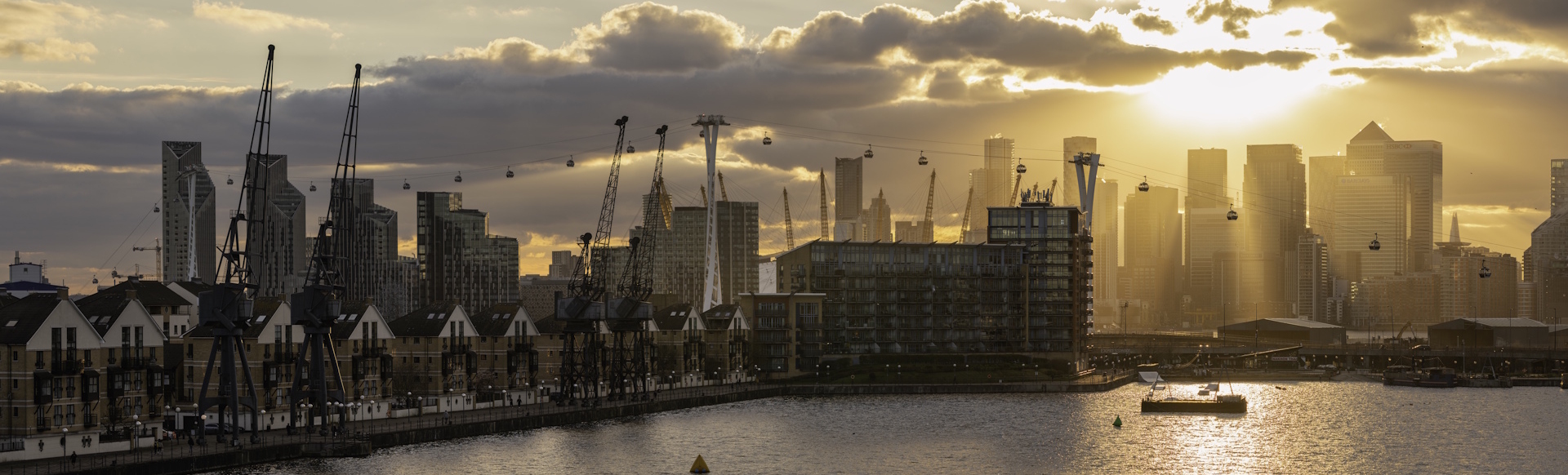 The Royal Docks at sunrise with the river Thames, the London Cable Car and Canary Wharf buildings in the distance.