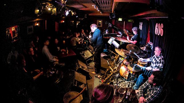 A band performs live on stage in front of tables of customers at 606 Club in Chelsea.