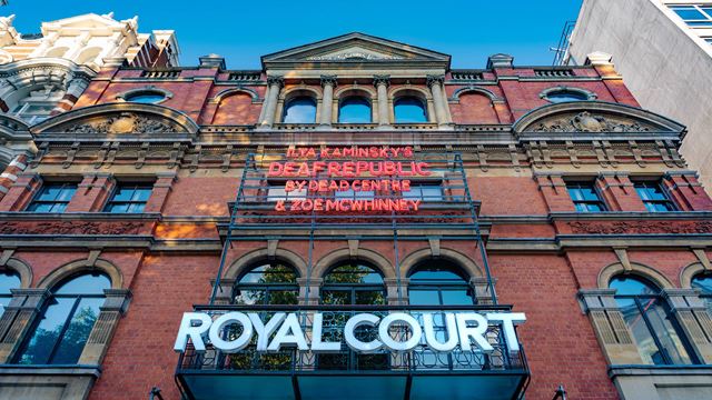 The brick facade of the Royal Court Theatre, featuring neon signage for the show and name of the theatre.