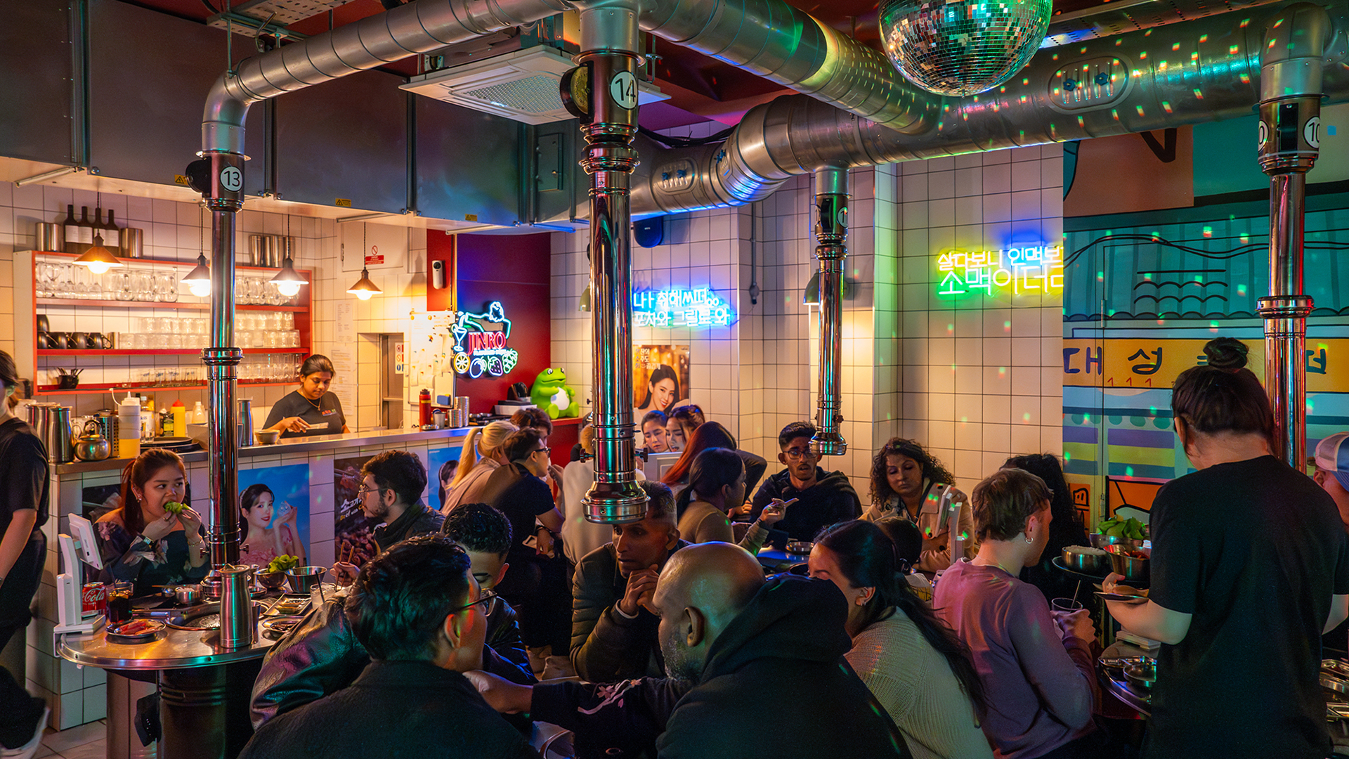 Diners enjoying Korean food and barbecue under a disco ball