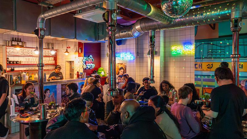Enjoy soul-warming Korean flavours at the retro-styled Pochawa Grill. Credit: Maguro Limited. Image courtesy of Maguro Limited. Diners enjoying Korean food and barbecue under a disco ball