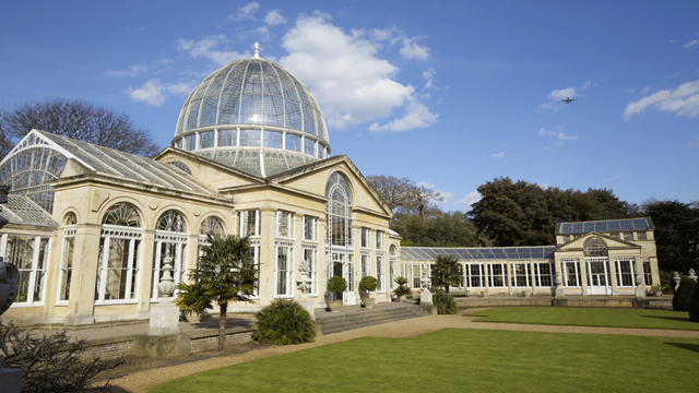 Syon House on a bright sunny day with lawn and trees outside