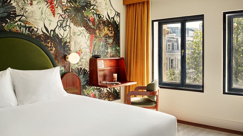 Choose from a range of gorgeous, bohemian-designed rooms inspired by the Victorian era. Credit: Hyde London City. Image courtesy of Hyde London City. Hotel bedroom with double bed with white sheets, green and red wallpaper, orange curtains and wooden furniture.
