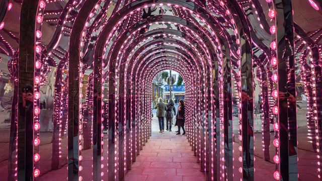 Inside Covent Garden's Infinity Chamber, a public art installation featuring illuminated mirrored arches.